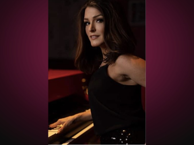 Tonya Scott at the piano in a dark venue, hands on the keys, lit in warm stage light